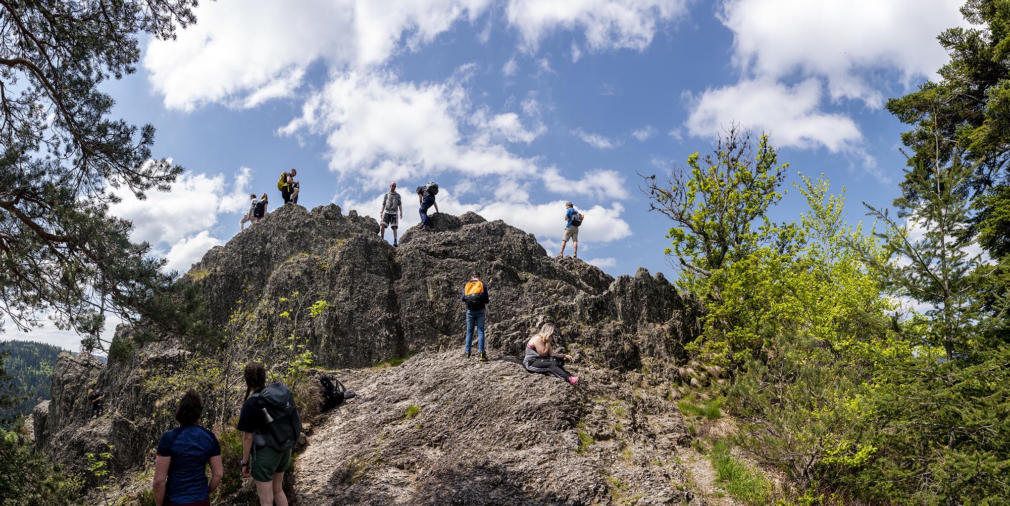 Blick auf den Gipfel des Klettersteigs Karlsruher Grat mit mehreren Wanderern und blauem Himmel mit kleinen Wölkchen